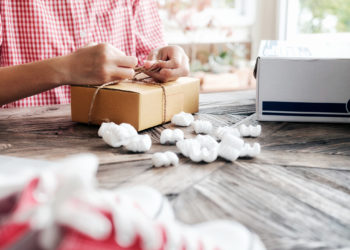 Young business start up online seller owner using computer for checking the customer orders from email or website and preparing packages for product office equipment.