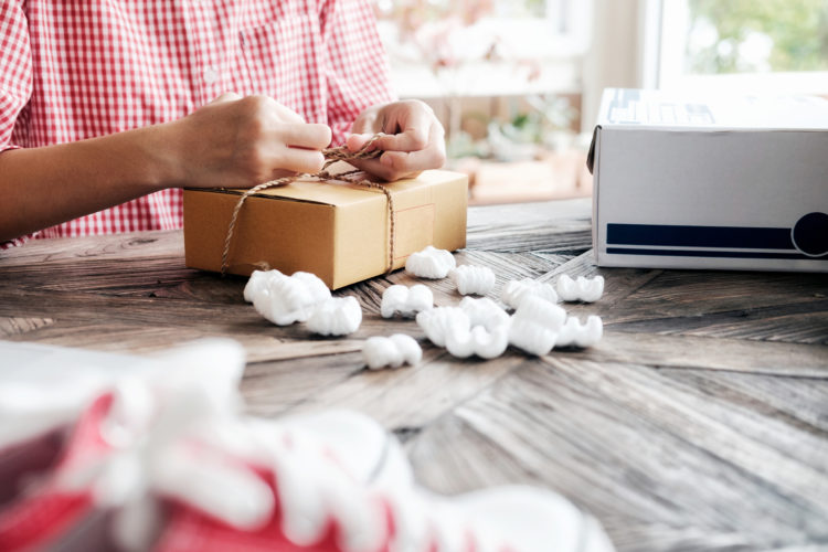 Young business start up online seller owner using computer for checking the customer orders from email or website and preparing packages for product office equipment.