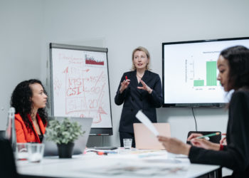Photo by Pavel Danilyuk from Pexels: https://www.pexels.com/photo/woman-in-black-blazer-presenting-in-a-meeting-8424484/