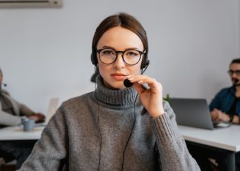 Photo by MART PRODUCTION from Pexels: https://www.pexels.com/photo/photo-of-a-woman-with-black-framed-eyeglasses-touching-a-microphone-7709207/