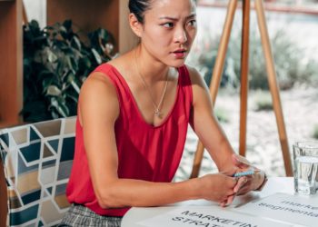 Photo by Kindel Media: https://www.pexels.com/photo/serious-asian-marketer-speaking-at-desk-with-papers-in-office-7688105/