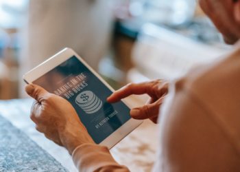 Photo by Gary  Barnes: https://www.pexels.com/photo/anonymous-man-working-remotely-on-tablet-during-breakfast-with-wife-in-kitchen-6248545/