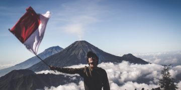 Photo by Dio Hasbi Saniskoro: https://www.pexels.com/photo/man-wearing-black-crew-neck-sweater-holding-white-and-red-flag-standing-near-mountain-under-blue-and-white-sky-1009949/