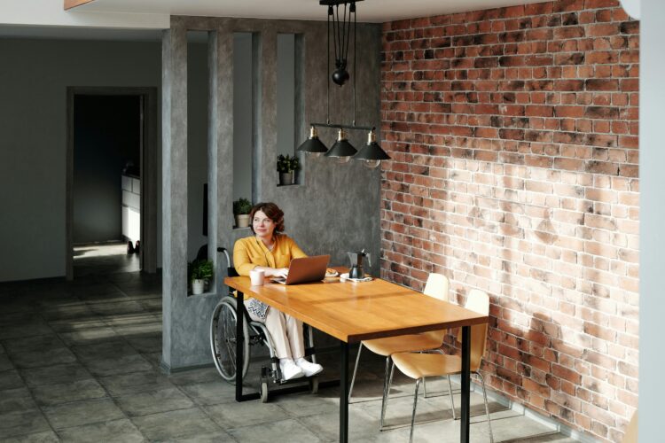 Photo by Marcus Aurelius: https://www.pexels.com/photo/a-woman-wearing-orange-long-sleeves-on-a-wheel-chair-beside-a-wooden-table-using-a-laptop-4064698/